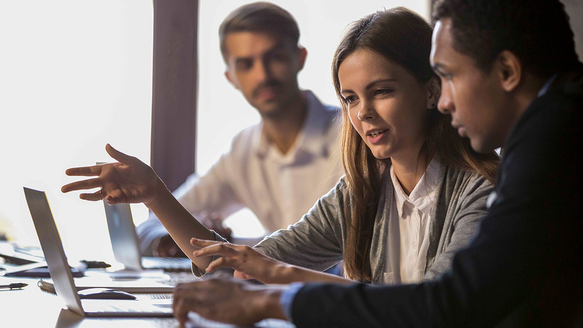 Three people in front of computers, talking about what's on the screen