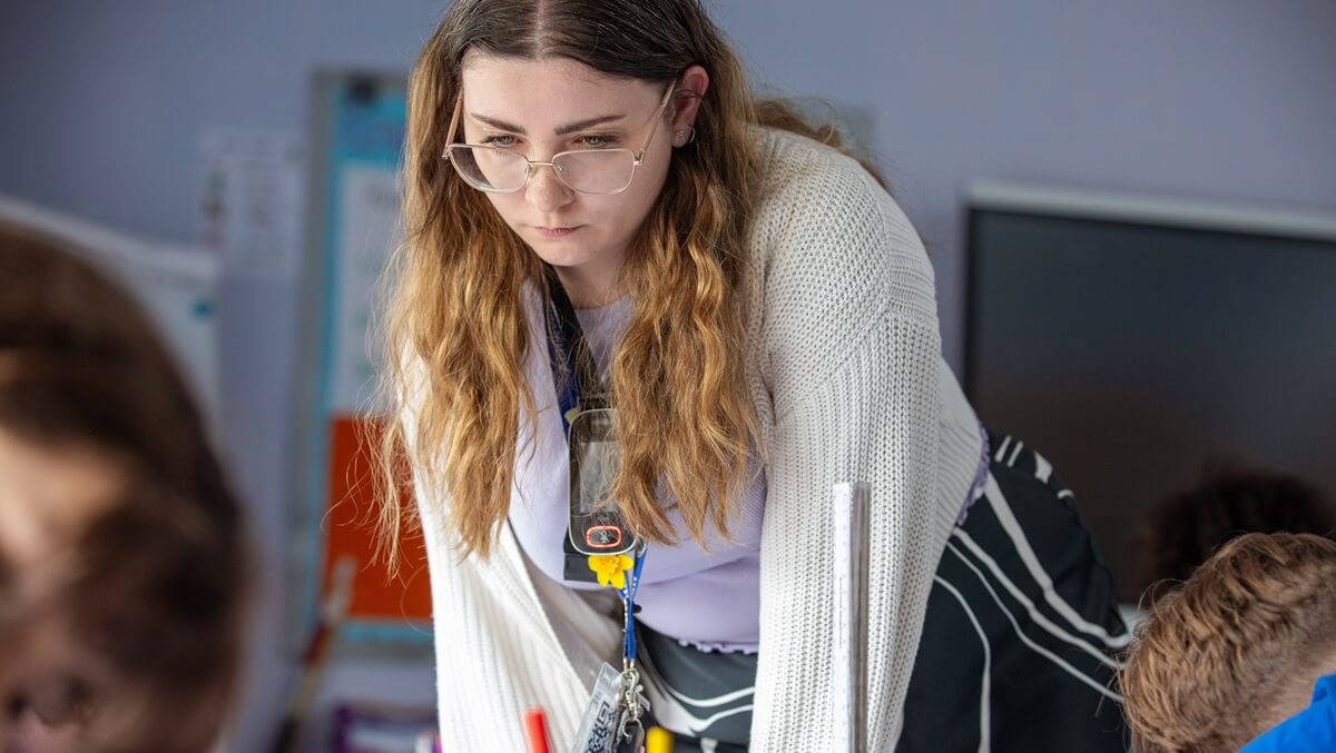 A teacher leaning across a desk