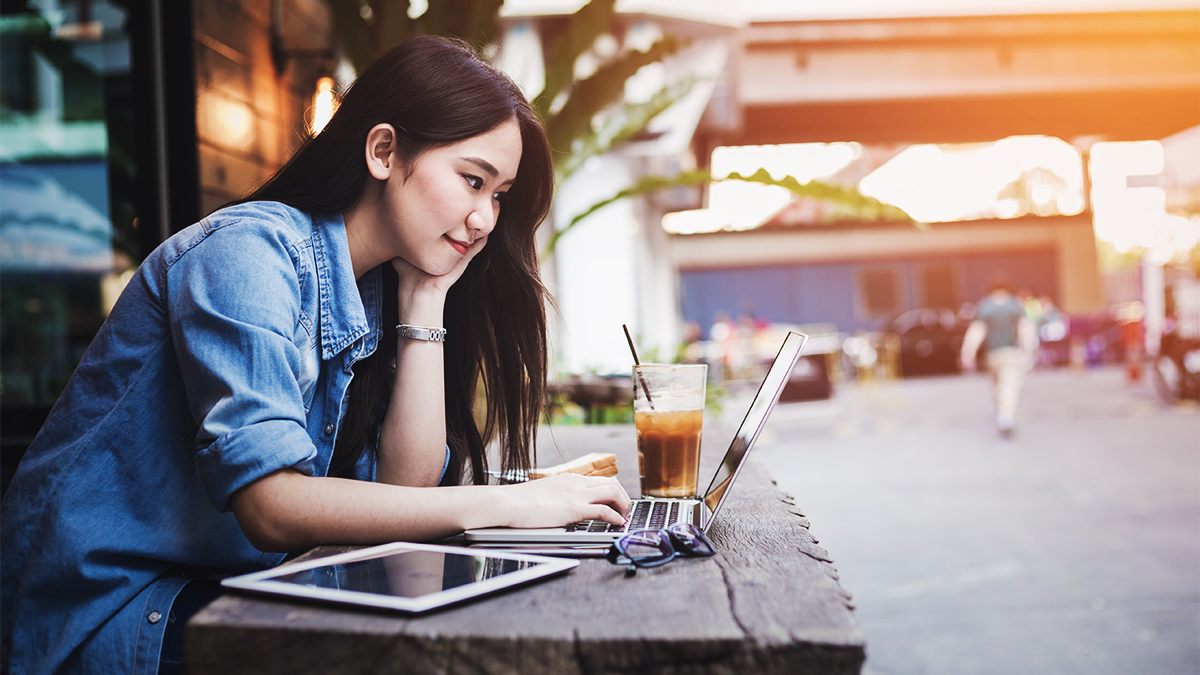 Student using her laptop sitting outside a cafe